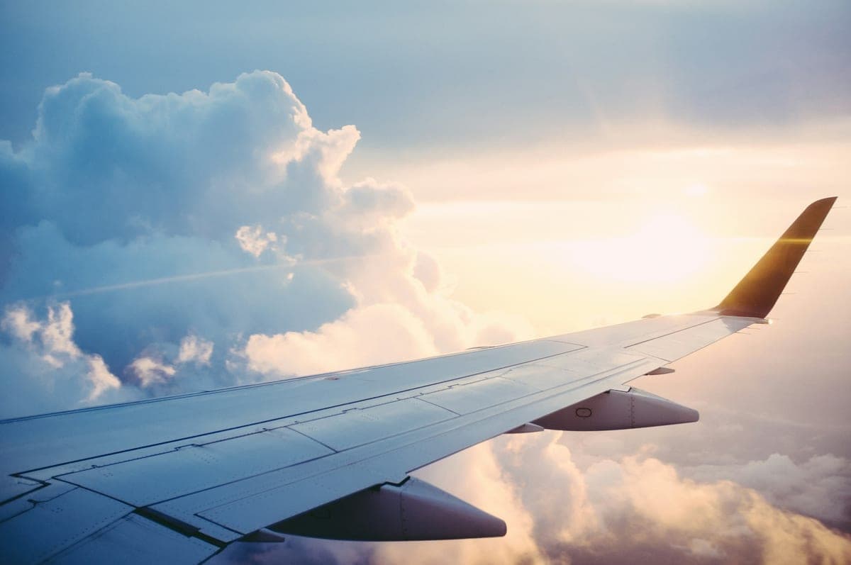 An aircraft wing above the clouds at sunset