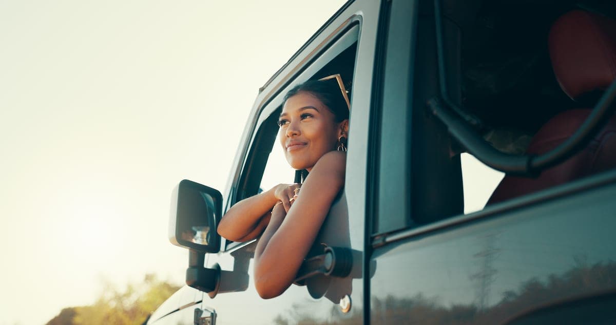 A traveller leaning out of a car window at sunset