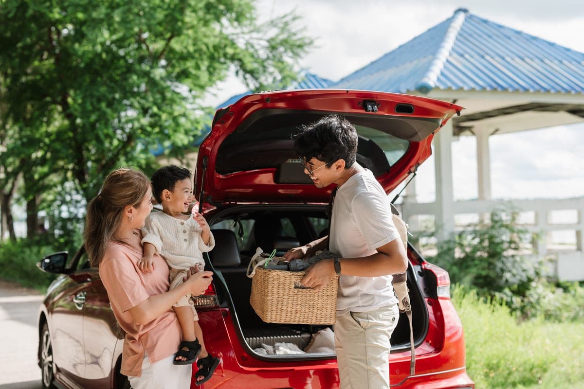 A family loading luggage into the boot of their rental car